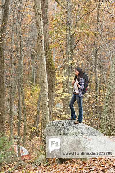 Young woman standing on stone in forest