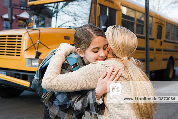 Umarmung von Mädchen und Mutter im Schulbus