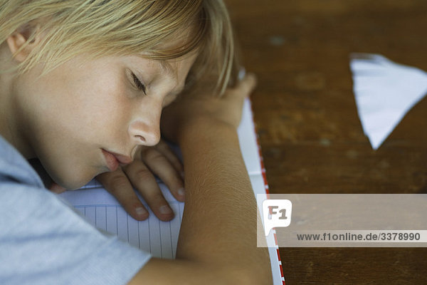 Preteen Junge schläft  ruht Kopf auf den Armen über das Notebook gelegt