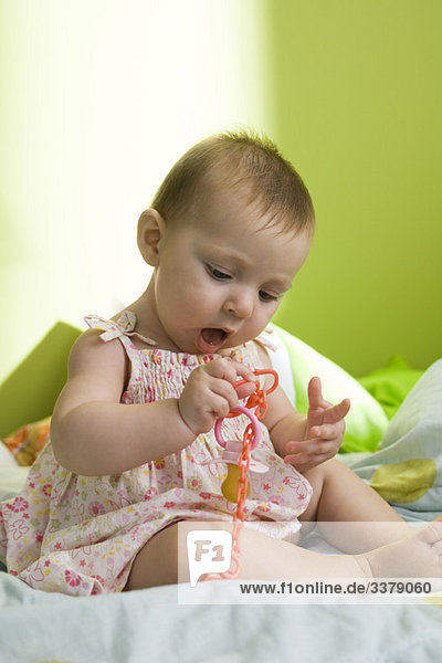 Kleinkind mit Spielzeugkette am Ende des Schnullers
