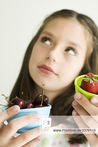 Mädchen entscheidet sich zwischen Kirschenschale und Erdbeerenschale