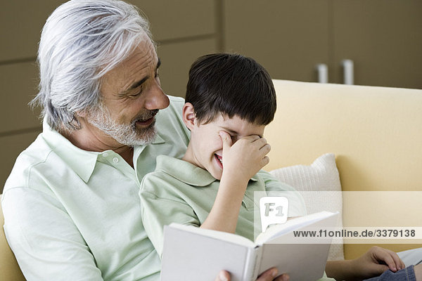 Älterer Mann liest dem Enkel die Geschichte vor.