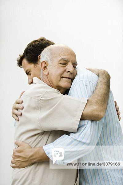 Älterer Mann umarmt erwachsenen Sohn