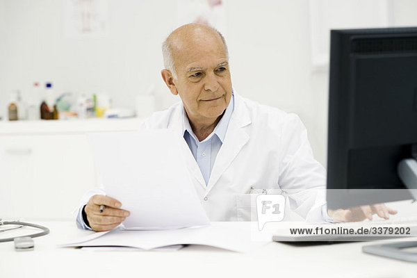 Arzt am Schreibtisch beim Ausfüllen der Papiere