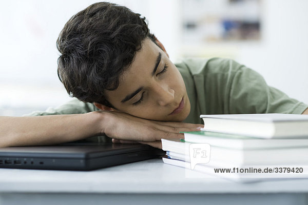 Männlicher Gymnasiast schläft am Schreibtisch