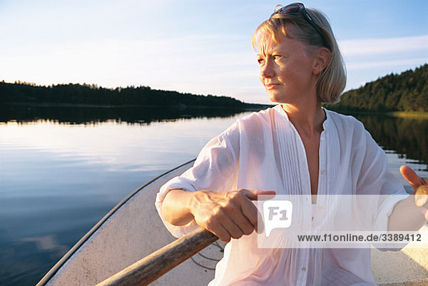 Frau Rudern auf einem ruhigen See bei Sonnenuntergang  Schweden.