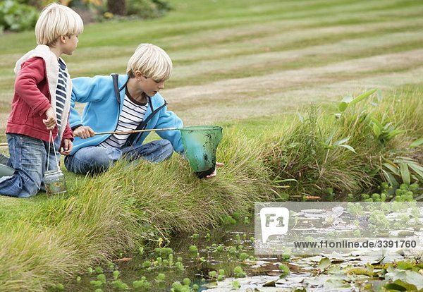 Brothers with fishing net near pond