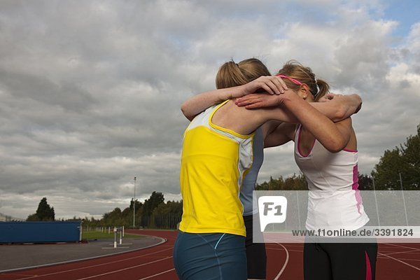 3 female athletes embracing