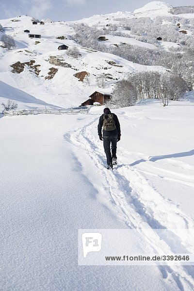 Mann  der durch Schnee in der Landschaft wandert