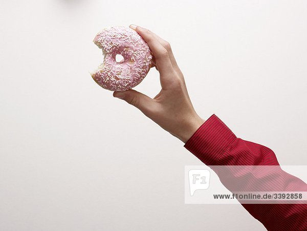 Eine Hand  die einen Donut hält.