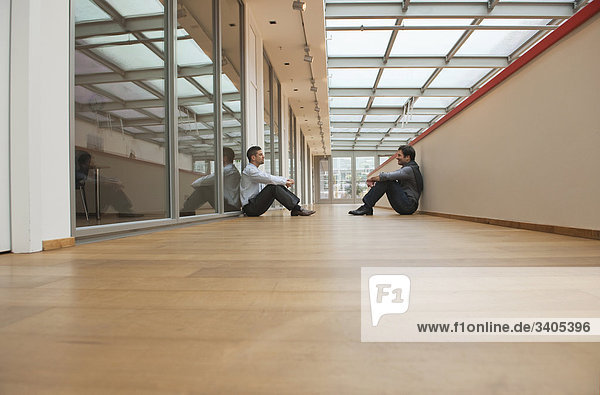 Zwei Geschäftsmänner sitzen auf dem Boden