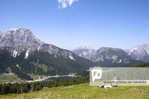 Two hikers on a meadow  view of Monte Cristallo and Lago di Misurina  Venetia  Italy  elevated view