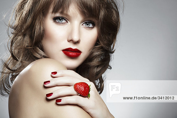 Junge Frau mit einem Ring aus einer Erdbeere mund