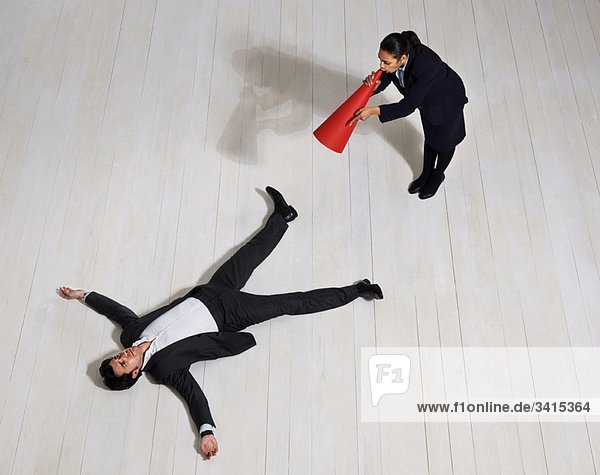 Geschäftsfrau schreit den Mann auf dem Boden an.