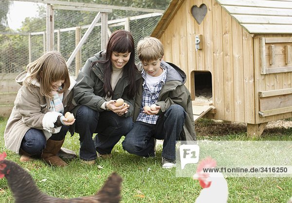 Mutter und Kinder beim Füttern von Hühnern