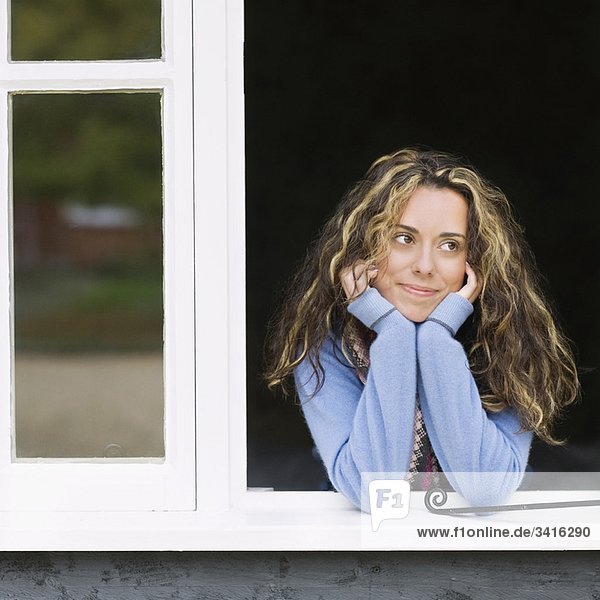 Lächelnde Frau schaut aus dem Fenster