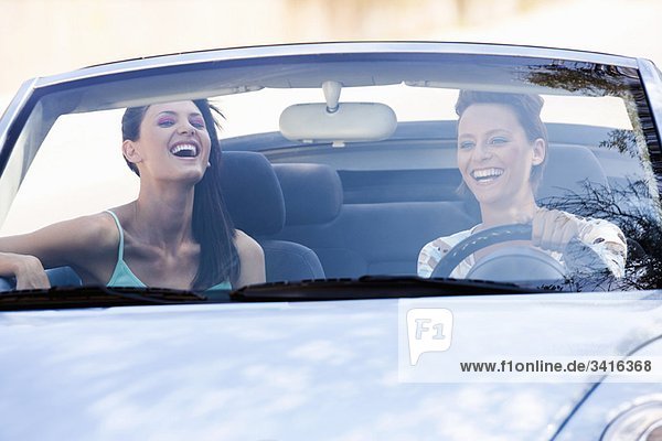 Zwei Frauen  die in einem Auto lächeln.