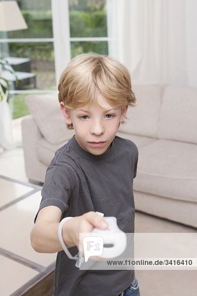 Ein Junge  der eine Spielkonsole zur Kamera zeigt.