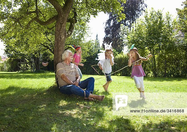 Enkelkinder binden Großvater an Baum