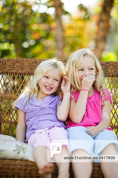 Sisters sitting on seat in garden