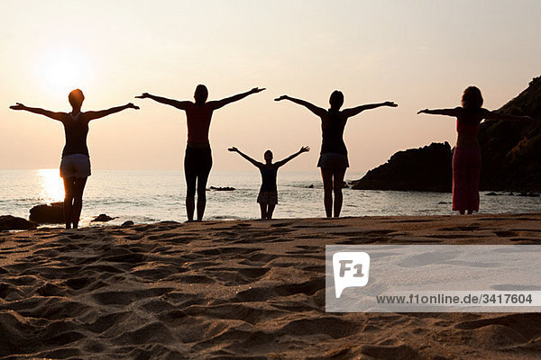 Frauen beim Yoga am Strand bei Sonnenuntergang