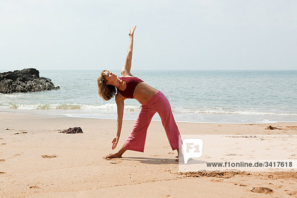 Frau Übendes Yoga am Strand