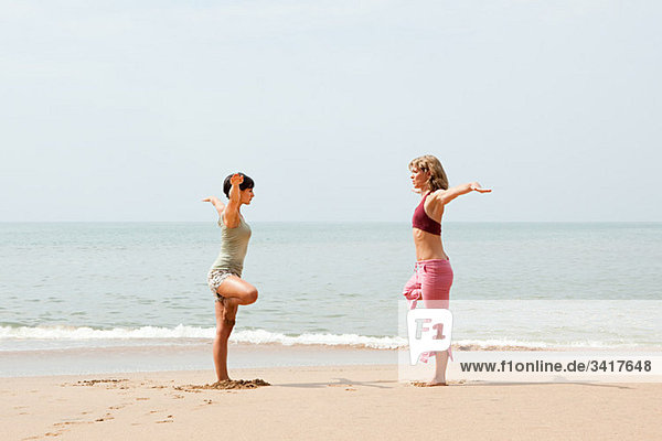 Zwei Frauen Übendes Yoga am Strand