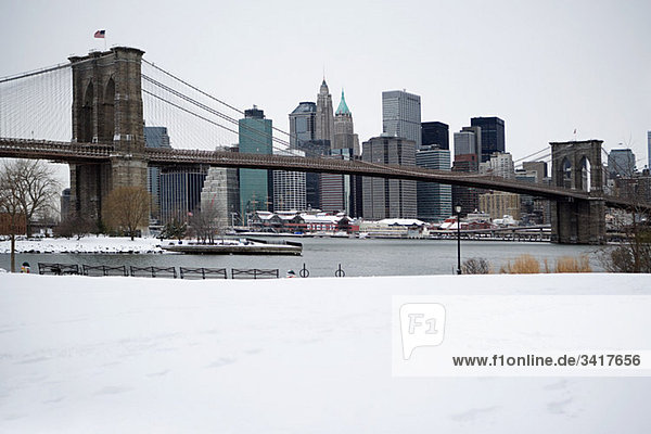 Brooklyn bridge and manhattan buildings in the snow