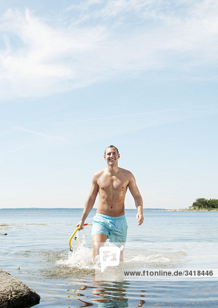 Mann  der vom Wasser auf den Strand zugeht