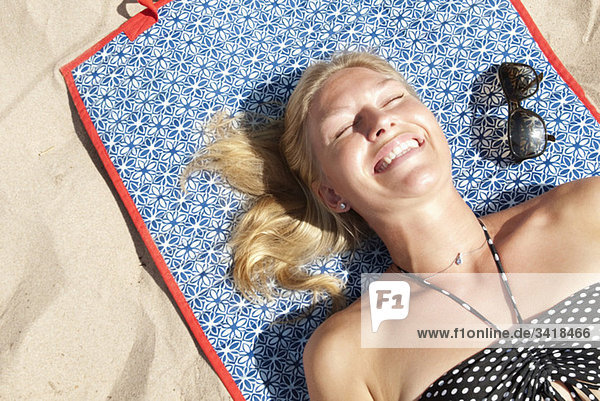 Frau am Strand liegend beim Sonnenbaden