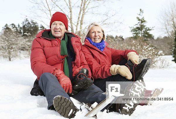 Mann und Frau sitzen draußen im Schnee.