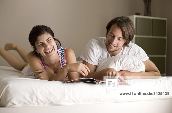Man and woman reading a magazine on bed  low angle view