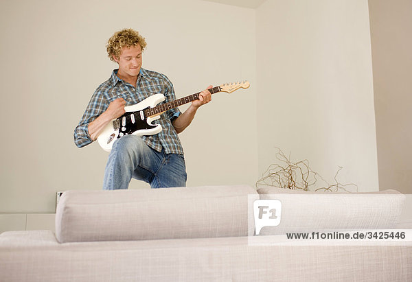 Mann spielt E-Gitarre in der Wohnung  Flachwinkelansicht
