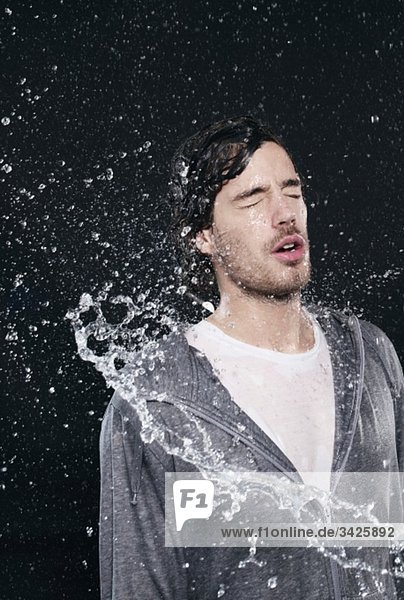 Man enjoying splash of water  eyes closed.