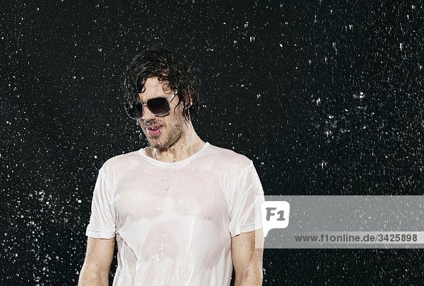Ein Mann  der im Regen steht und eine Sonnenbrille trägt.