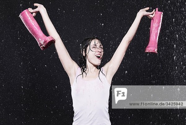 Woman holding rubber boots  arms up.