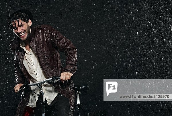 Mann mit Fahrrad im Regen  lächelnd.