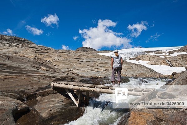 Austria  Grossglockner  Woman standing on Wooden bridge over mountain stream