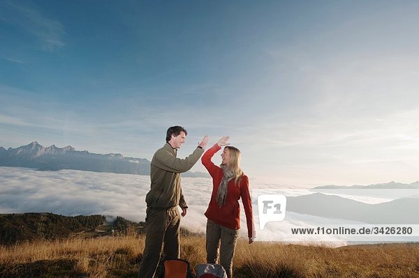 Austria  Steiermark  Reiteralm  Couple of hikers exchanging high-fives  laughing  portrait