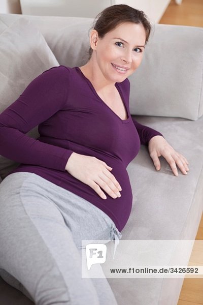 Schwangere auf der Couch liegend  lächelnd  Portrait