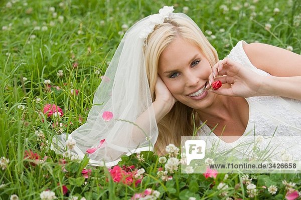 Bride lying on meadow  smiling  portrait.
