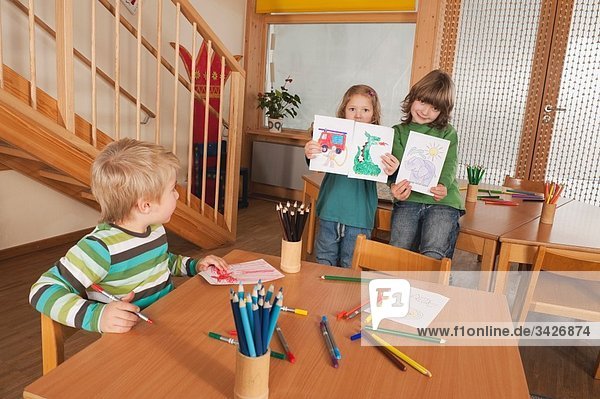 Deutschland  Kinder im Kindergarten  Mädchen (4-5)  (6-7) im Hintergrund mit Gemälden  lächelnd  Portrait