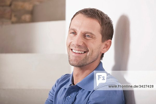 Man sitting on steps of staircase  smiling  portrait  close-up