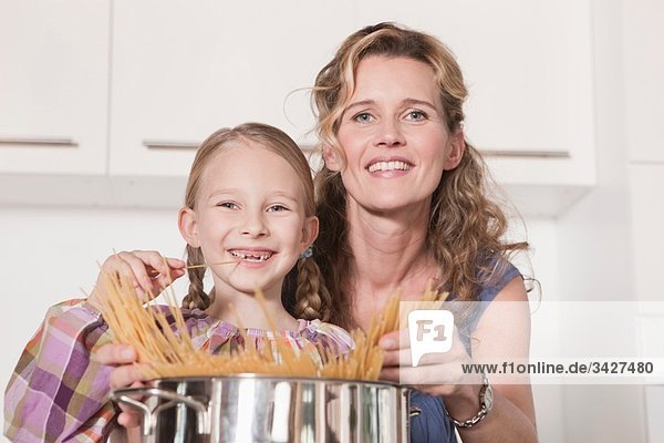 Deutschland  Köln  Mutter und Tochter (6-7) kochen Pasta  lächelnd  Portrait