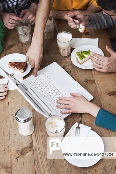 Freunde  die einen Laptop benutzen  frühstücken.