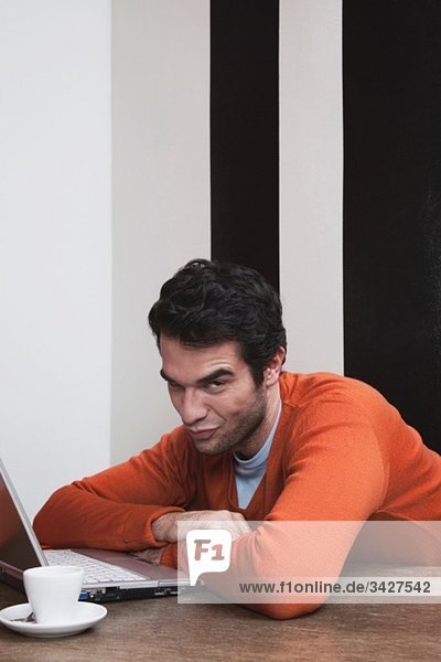 Man raised eyebrows with laptop and coffee cup