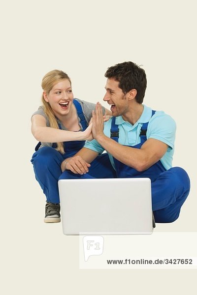 Mann und Frau in der Gesamtheit mit Laptop  so dass High-Five