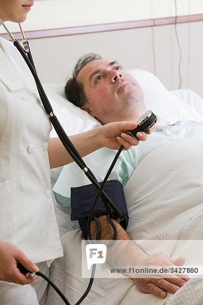 Krankenschwester mit Blutdruckmesser am Patienten