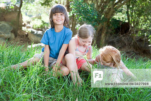 Kinder sitzen auf Rasen