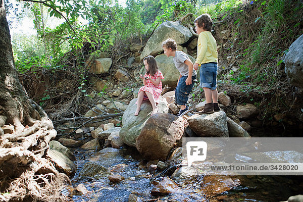 Kinder auf Felsen am Fluss